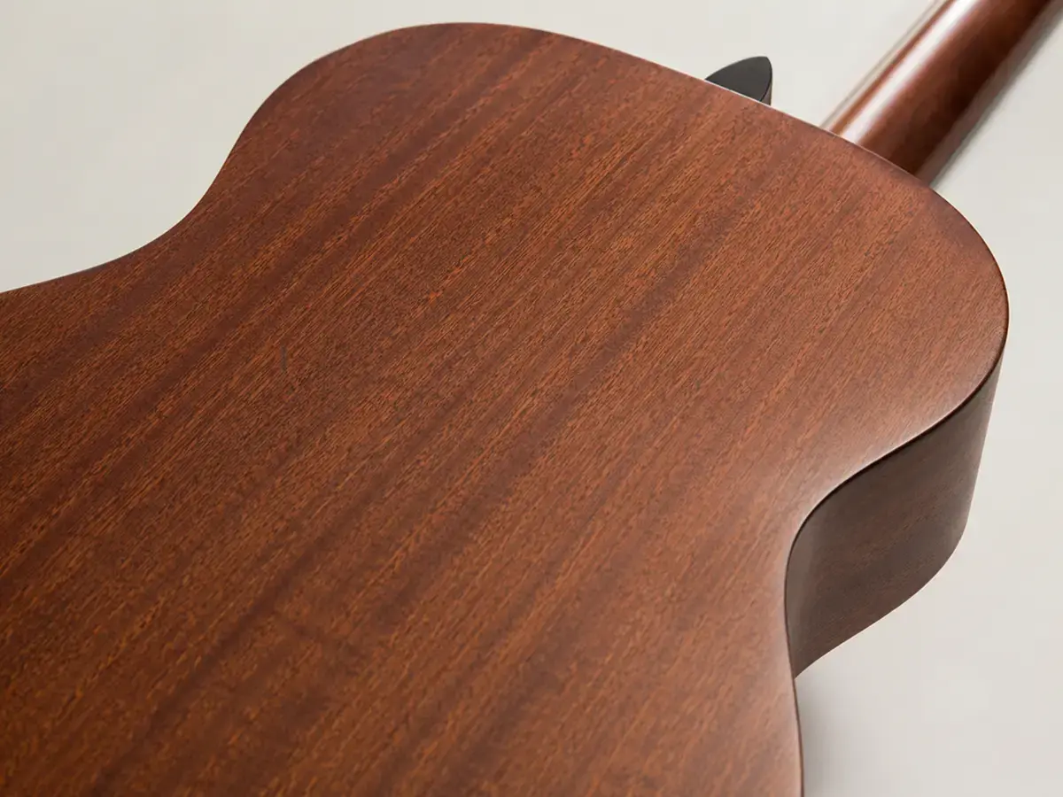Close-up of a mahogany acoustic guitar back and sides showing its reddish-brown grain